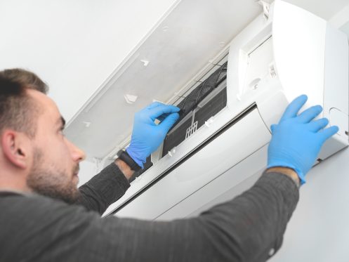 Technician replacing filter in air conditioner